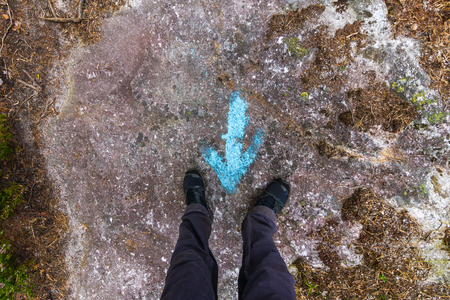 Woman standing at a blue painted direction arrow on the groundの写真素材