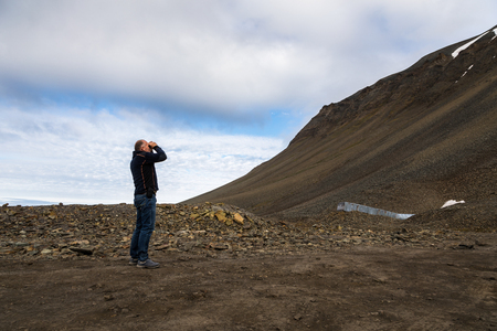 Man using binoculars in the mountains at Svalbardの写真素材