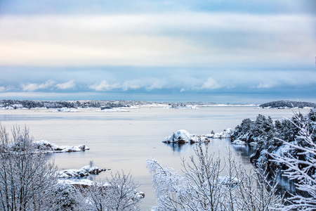 Beautiful winter day at Odderoya in Kristiansand, Norway. Trees covered in snow. The ocean and archipelago in the background.の写真素材