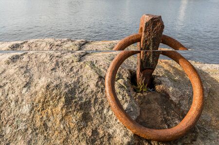 Rusty ring for the mooring of a boat on the rock by the oceanの写真素材