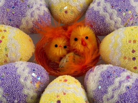 Two red Easter chicks in the nest surrounded by decorated eggsの写真素材