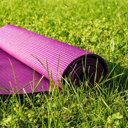 Rolled Yoga mat on green grass with sunlight, close up. Sport in nature conceptの写真素材