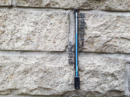 Closeup of a wall thermometer on a brick wall outdoorsの写真素材