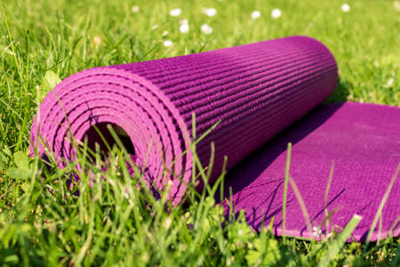 Yoga mat on green grass, close up. Outdoor sport equipmentの写真素材