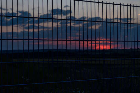 Background with metal grids against sunset sky. Boundary, fence, hope conceptの写真素材