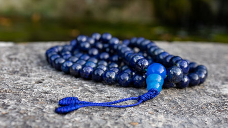 Blue buddhist mala ptayer beads (lapislazuli) on stone, close up. Mindfulness and japa meditation accessory.の写真素材