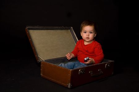 Surprised boy holding phone in luggageの写真素材