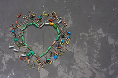 Heart shape made from electronic components on gray concrete background. Symbol of love from resistors and capacitors. Happy Valentines Day greeting card. Flat lay with space for textの写真素材