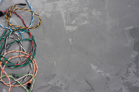Colored cables and wires with connectors on gray concrete background. Colorful computer wires. Telecommunications. Blank for postcard with space for text. flat layの写真素材