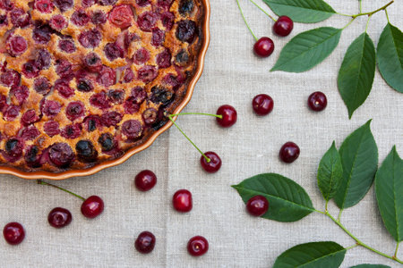 Delicious cherry clafoutis in round baking dish on light background. Fresh homemade berry pie. Traditional French dessert. top view. selective focusの写真素材