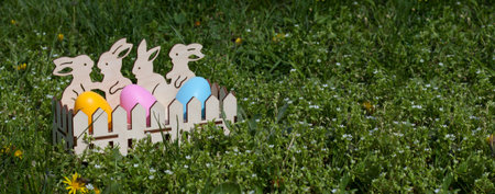 Easter banner with space for text. Cute wooden egg cup with painted Easter eggs standing on green...