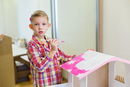 little girl is painting a house for dollsの写真素材