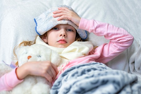 A sick little girl takes medication and eats fruit.の写真素材