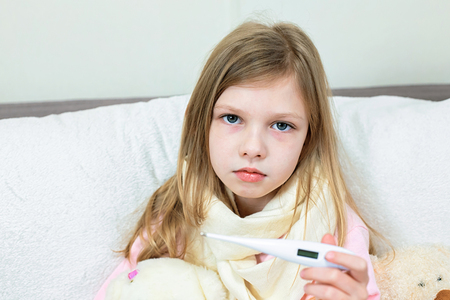 A sick little girl takes medication and eats fruit.の写真素材