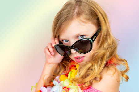 beautiful little girl in a pink dress, sunglasses and hat from the sun on a bright flat background, place for textの写真素材