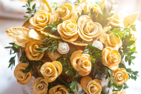 A vibrant display of yellow roses and greenery in a charming pot set on a sunlit surface.の写真素材