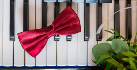 A vibrant red satin bow tie is elegantly placed on piano keys, adding a touch of sophistication to the musical ambiance.の写真素材