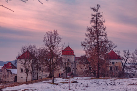 A group of visitors explores the enchanting castle ruins as twilight descends over the snow-covered grounds.の写真素材