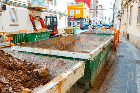 Construction Site With Debris Containers Filled With Dirt and Rubble on a Busy Urban Street