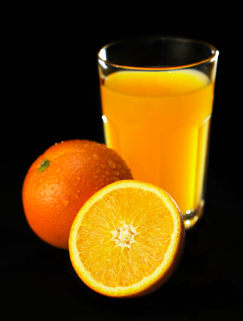 glass of orange juice with an orange and a half-cut orange by the sideの写真素材