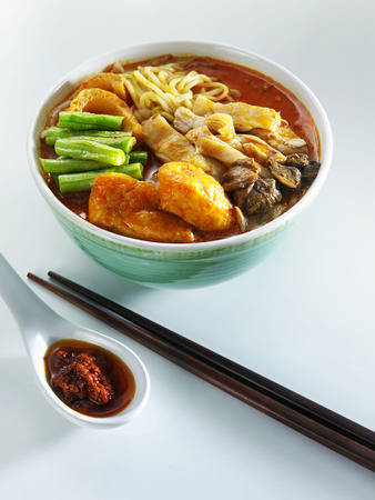 Malaysia food-bowl of curry noodle with a pair of black chopsticks and a spoonful of sambal with soy sauceの写真素材