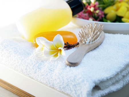 Shampoo, bar of soap, hairbrush and flower on a towelの写真素材
