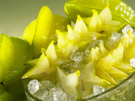 Three starfruits and a bowl of cut starfruits with iceの写真素材