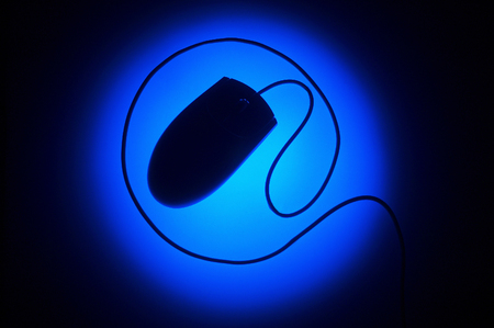 Top angle view of the silhouette of a computer mouse under a blue lightの写真素材