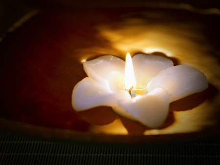 A burning flower shaped candle floatingの写真素材