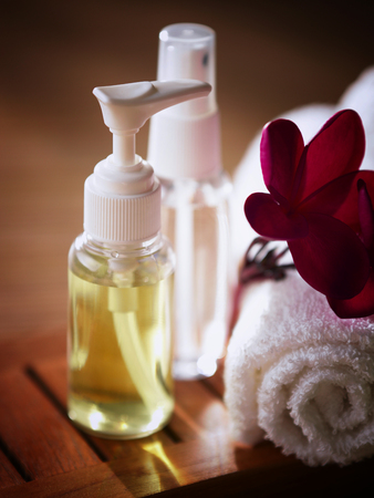 cosmetic bottles with towel and flowerの写真素材