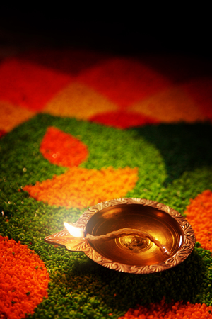 Diwali oil lamp - Diya lamp lit on colorful rangoliの写真素材