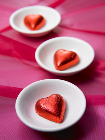 three red heart shape chocolate on the small plateの写真素材