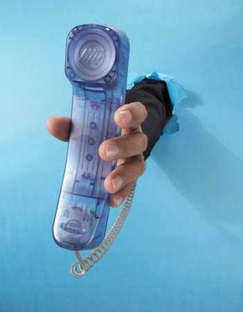 hand through paper holding a phone set
