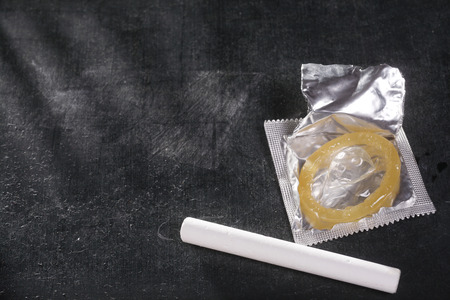 stock image of the condom in front of blackboardの写真素材