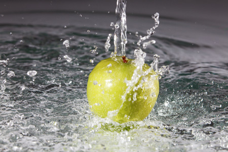 Water being poured onto apple.の写真素材