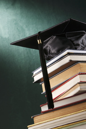 Graduation cap with book  in front of black boardの写真素材