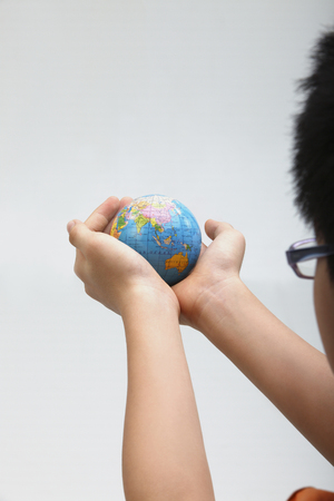 boy holding a globe on the plain backgroundの写真素材