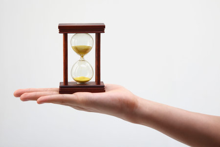 hand holding an hour glass on the plin background
