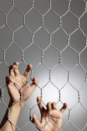 depression - close up of hand on chain-link fence.の写真素材