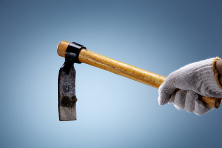 Hand holding garden trowel on coloured background.の写真素材