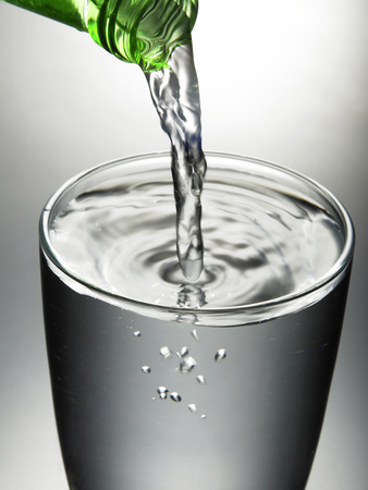 Water poured from a bottle into a glass.の写真素材