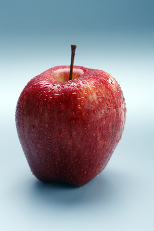 Wet red apple isolated on coloured background.の写真素材