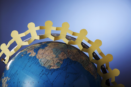 Paper chain standing on a globe.の写真素材