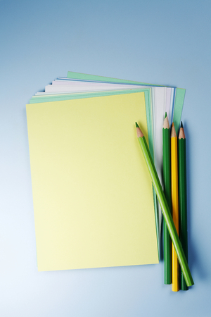 Coloured paper with a stack of colour pencils isolated on the blue background.の写真素材
