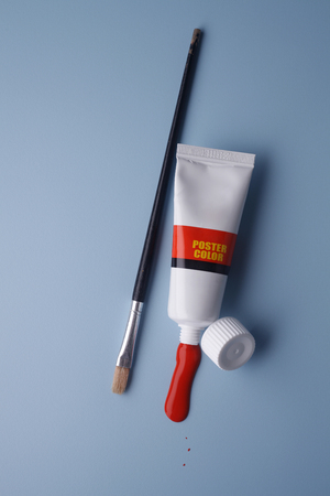 Paintbrush with a tube of paint isolated on blue background.の写真素材