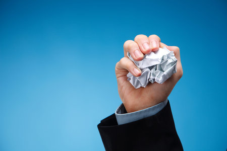 Human hand holding a scrunched up paper.
