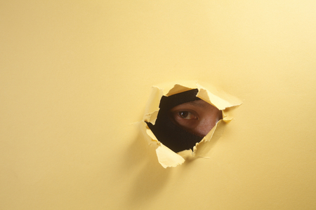 stock image of thief peeping through a holeの写真素材