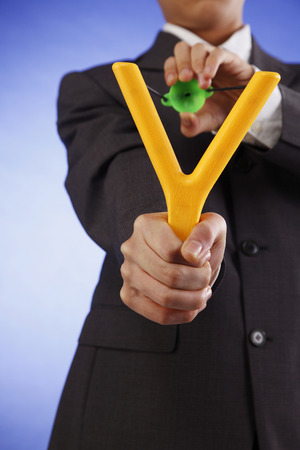 bussineman holding catapult aiming to cameraの写真素材