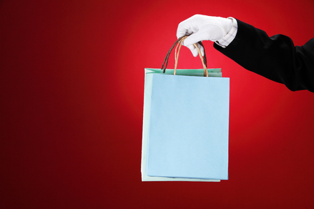 Doorman wearing white gloves, holding shopping bagsの写真素材