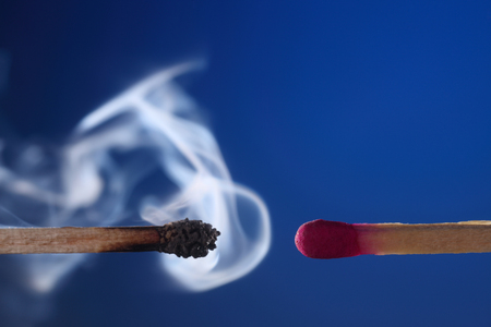 burnt match with smoke next to matchstickの写真素材